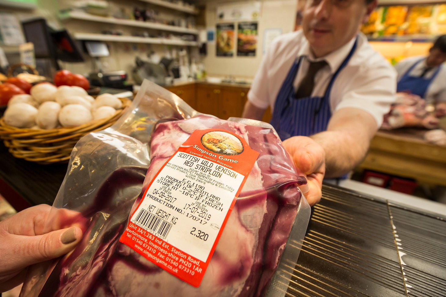 Butcher handing over wild venison from Scotland.